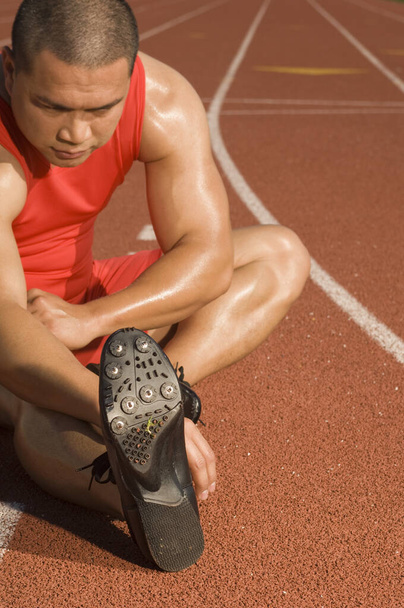 Mature male athlete stretching on racetrack - Photo, Image