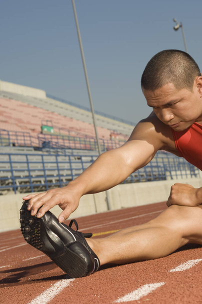 Mature male athlete warming up before starting race - Photo, Image