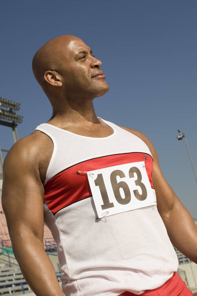 Confident African American male runner in stadium looking away - 写真・画像