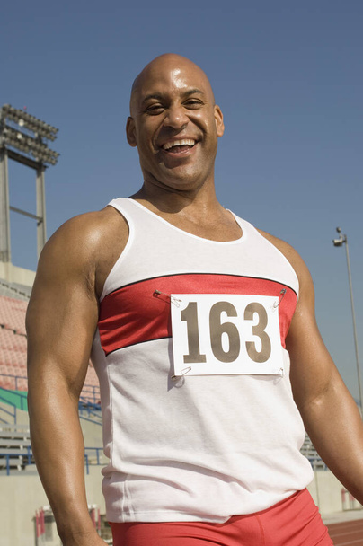 Portrait of cheerful African American male athlete in stadium - Photo, image