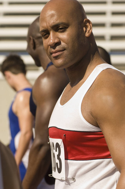 Portrait of confident African American male athlete with competitor in stadium - Foto, Imagem