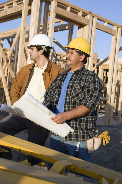 Male construction workers with blueprint at site - Foto, imagen