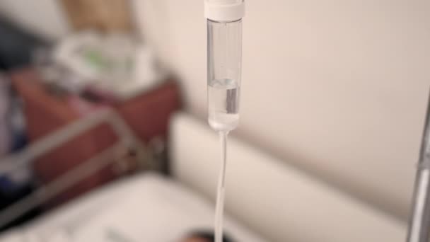 Zbliżenie kroplówki z roztworem soli fizjologicznej dla pacjenta i pompy infuzyjnej na rozmytym tle luksusowego pokoju VIP w szpitalu. - Materiał filmowy, wideo