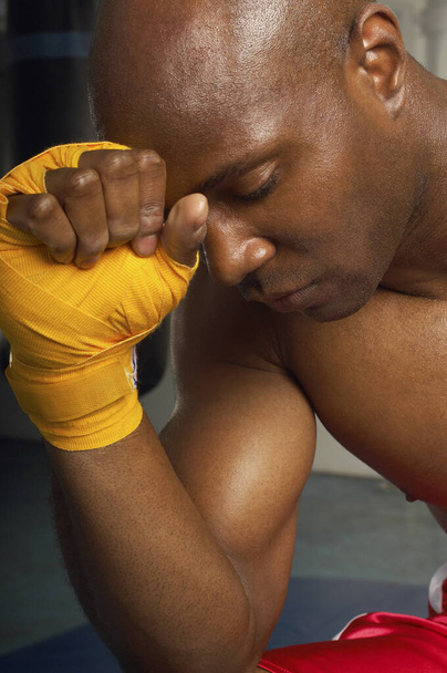 Close-up of an upset African American male boxer with head on wrapped hand - Fotografie, Obrázek