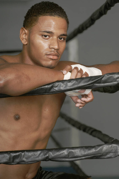 Portrait of a young African American boxer standing by boxing ring - 写真・画像