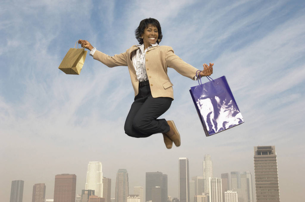 Portret wesołej starszej bizneswoman skaczącej w powietrzu z torbami na zakupy - Zdjęcie, obraz