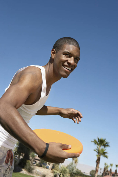 Young African American man ready to throw flying disc - Фото, зображення