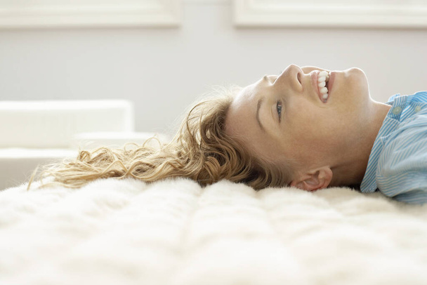 Happy Caucasian female relaxing on bed - Фото, изображение