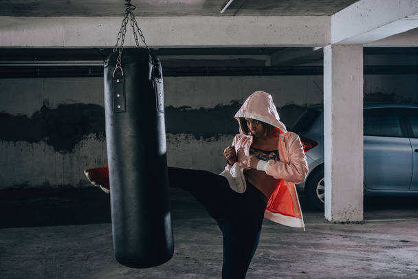 Junge Sportlerin beim Boxtraining in einer Garage. - Foto, Bild