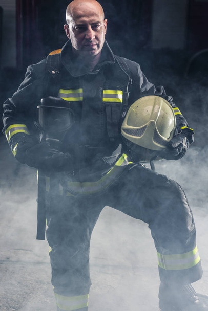 Fireman de pie confiando en mantener casco y usar bomberos - Foto, imagen