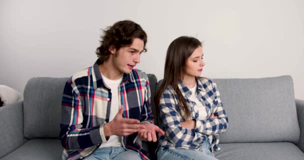 Mladý muž gestikuluje při rozhovoru s uraženou přítelkyní v obývacím pokoji - Záběry, video