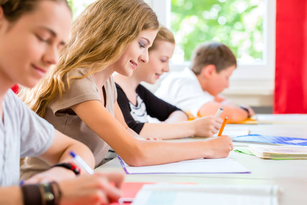 Students or pupils of school class writing an exam test in classroom concentrating on their work - Фото, изображение