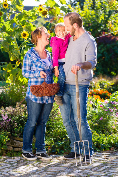 Family with mother, father and daughter gardening in garden - 写真・画像