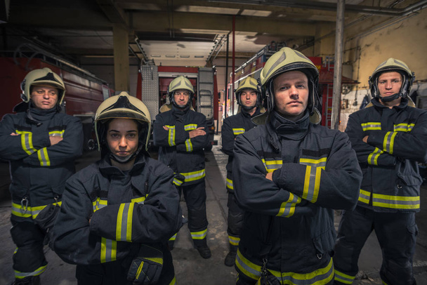 Een groep brandweermannen met zelfvertrouwen met gekruiste wapens. Vuur - Foto, afbeelding