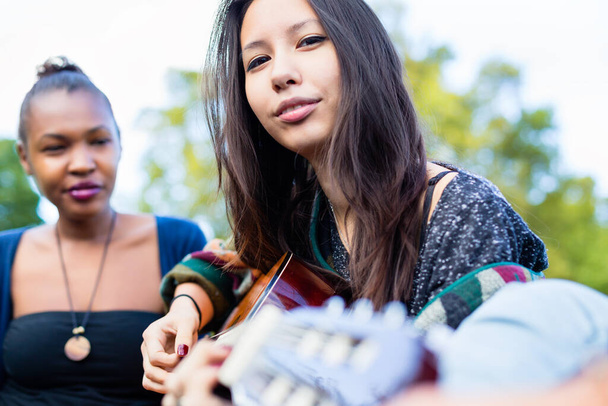 Guitar player Asian girl making music with friends in park - Foto, Imagem