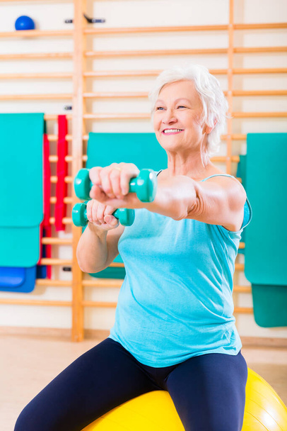 Senior woman doing fitness sport in gym with dumbbells - Photo, Image