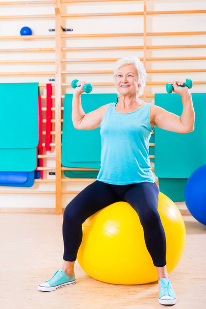 Senior woman doing fitness sport in gym with dumbbells - Zdjęcie, obraz