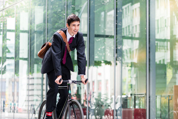 Cheerful young employee with a healthy lifestyle riding an utility bicycle to a modern workplace in Berlin - Photo, Image