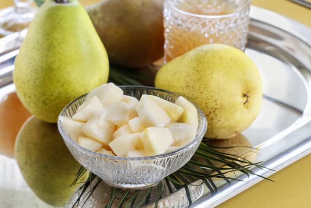 Sliced pear in a crystal bowl. Fruit drinks in the background.  - Photo, image