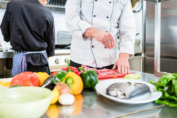 Chef putting salt on fish while cooking in kitchen seasoning the food - Φωτογραφία, εικόνα