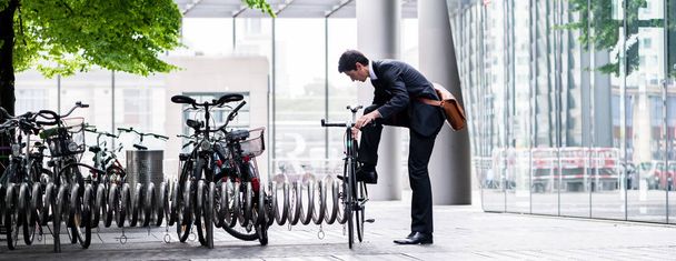Businessman parking his bicycle in town at a bicycle rack after commuting to work in a concept of eco-friendly transport and healthy active lifestyle, panoramic banner view - Foto, Imagen