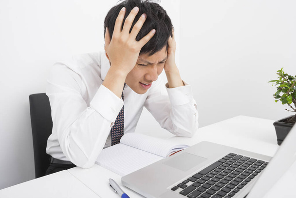 Frustrated businessman with head in hands sitting at desk in office - Foto, Imagem