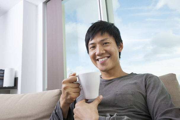 Portrait of mid adult man holding coffee cup in house - 写真・画像