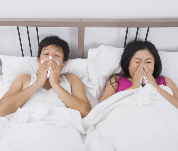 Young couple blowing noses in bed - Photo, Image