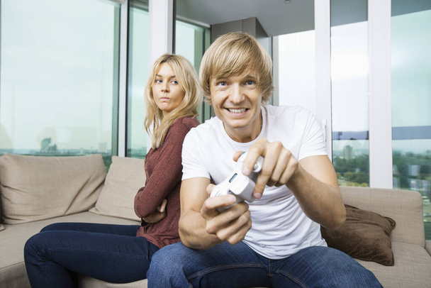 Angry woman looking at man play video game in living room at home - Photo, Image