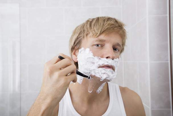Portrait of mid-adult man shaving in bathroom - Photo, Image