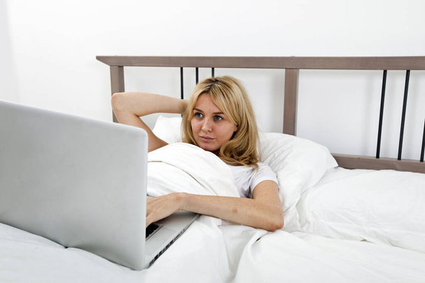 Young woman looking at laptop in bed - Foto, immagini