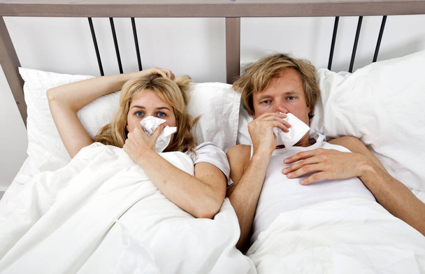 Portrait of couple suffering from cold lying on bed - Фото, изображение