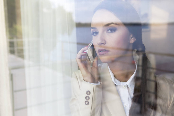 Confident businesswoman using cell phone in office - Photo, image