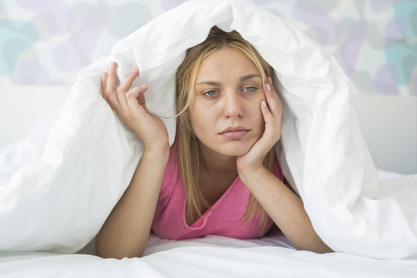 Thoughtful ill woman covered with quilt in bed - Photo, image