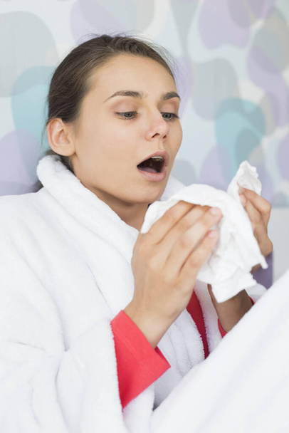 Young woman suffering from cold sneezing at home - Фото, изображение