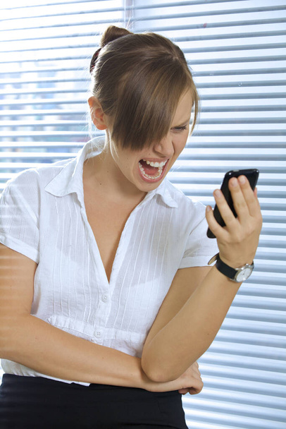 Angry businesswoman looking at a mobile phone - Foto, Imagen