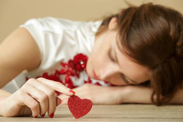 Smutna samotna kobieta z czerwonym sercem. Bycie samemu w Walentynki. Pojęcie złamanego serca, rozwodu lub zerwania. - Zdjęcie, obraz