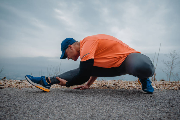 Athletic older man in sport clothes stretching before running - Photo, Image