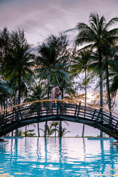 pari katsomassa auringonlaskua rannalla ja uima-allas ylellisyyttä keinona Thaimaassa Khao Lak
 - Valokuva, kuva