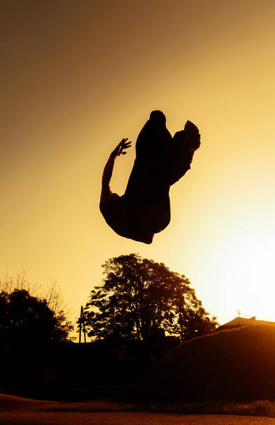 junger, fitter Mann fliegt durch die Luft, während er einen Salto Salto rückwärts macht - Foto, Bild