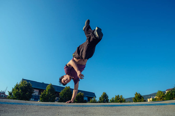 Şehir merkezinde genç bir atletik tarafından yapılan amuda kalkma hareketi. - Fotoğraf, Görsel