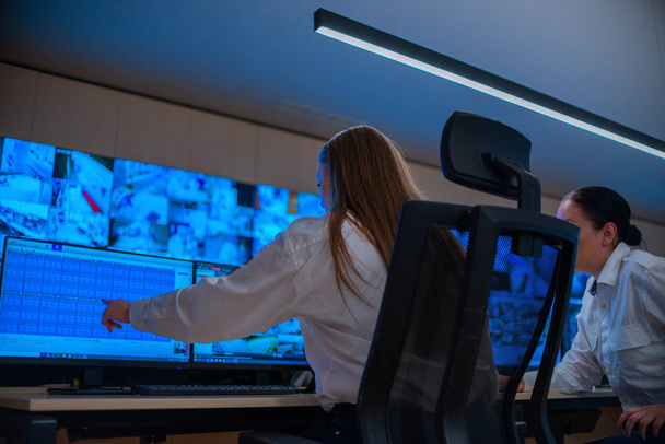 Güvenlik veri merkezi operatörleri (yöneticiler) birden fazla monitöre bakarken bir CCTV izleme odasında bir grupta çalışırlar (bilgisayar ekranları)) - Fotoğraf, Görsel