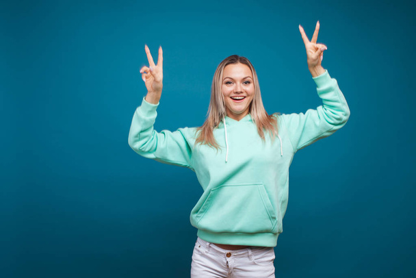 Happy girl smiling, portrait in Studio on blue background. Positive young blond woman - Foto, Imagen