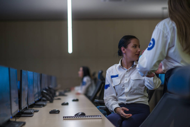 Ο φρουρός ασφαλείας παρακολουθεί σύγχρονες κάμερες κλειστού κυκλώματος σε ένα δωμάτιο παρακολούθησης. Γυναίκες σεκιουριτάδες που παρακολουθούν τη συνομιλία τους στο CTV. - Φωτογραφία, εικόνα