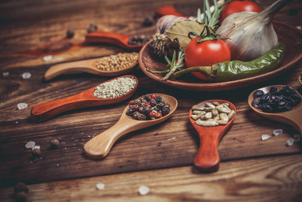 Different spices in wooden spoons and different ingredients for cooking, cherry tomatoes, garlic, coriander and red pepper - Foto, Bild