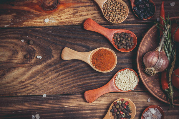 Different spices in wooden spoons and different ingredients for cooking, cherry tomatoes, garlic, coriander and red pepper - Zdjęcie, obraz