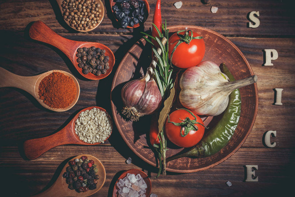 Different spices in wooden spoons and different ingredients for cooking, cherry tomatoes, garlic, coriander and red pepper - Foto, immagini