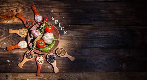 Different spices in wooden spoons and different ingredients for cooking, cherry tomatoes, garlic, coriander and red pepper - Fotografie, Obrázek