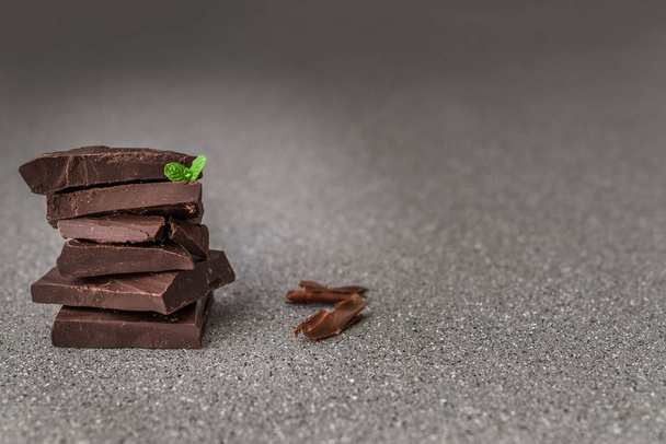 A stack of dark milk chocolate against gray stone background. - Фото, изображение