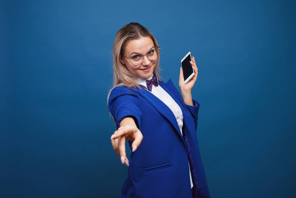 Cute and funny businesswoman in a stylish blue jacket and bow tie uses a smartphone. - Φωτογραφία, εικόνα